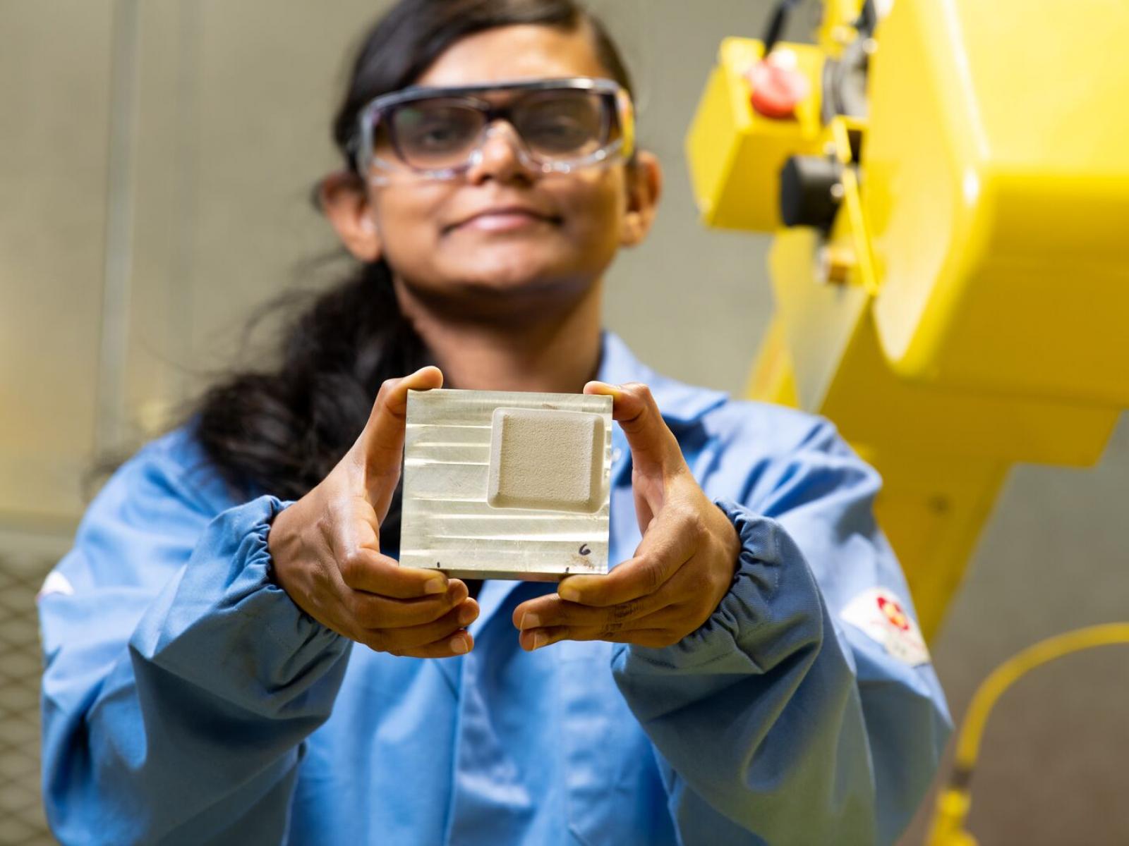 Woman in lab coat holding metal