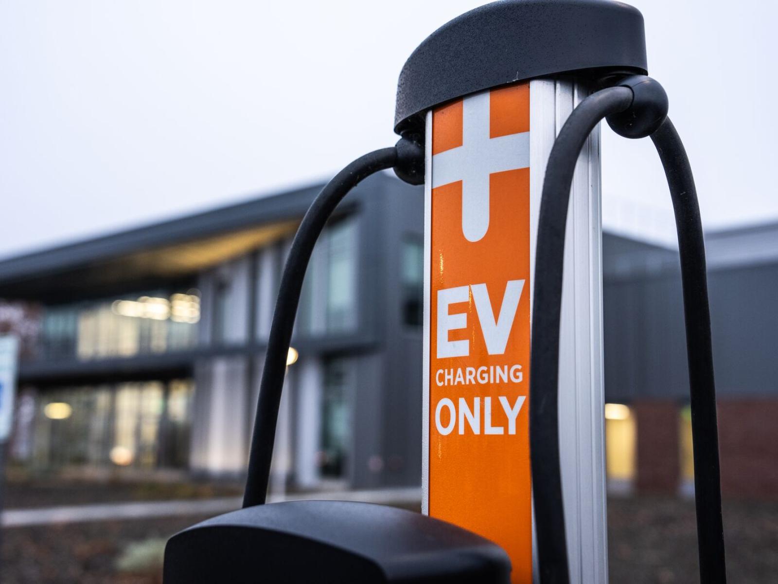 A commercial electric vehicle charger in the foreground with the Grid Storage Launchpad building in the background.