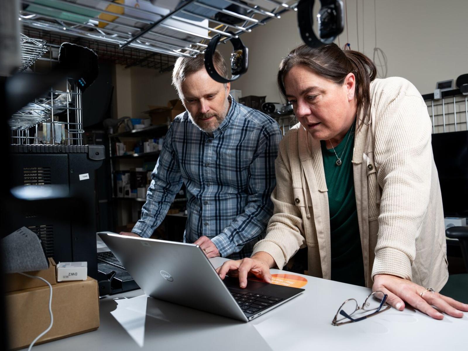 two people standing in a lab looking at a laptop