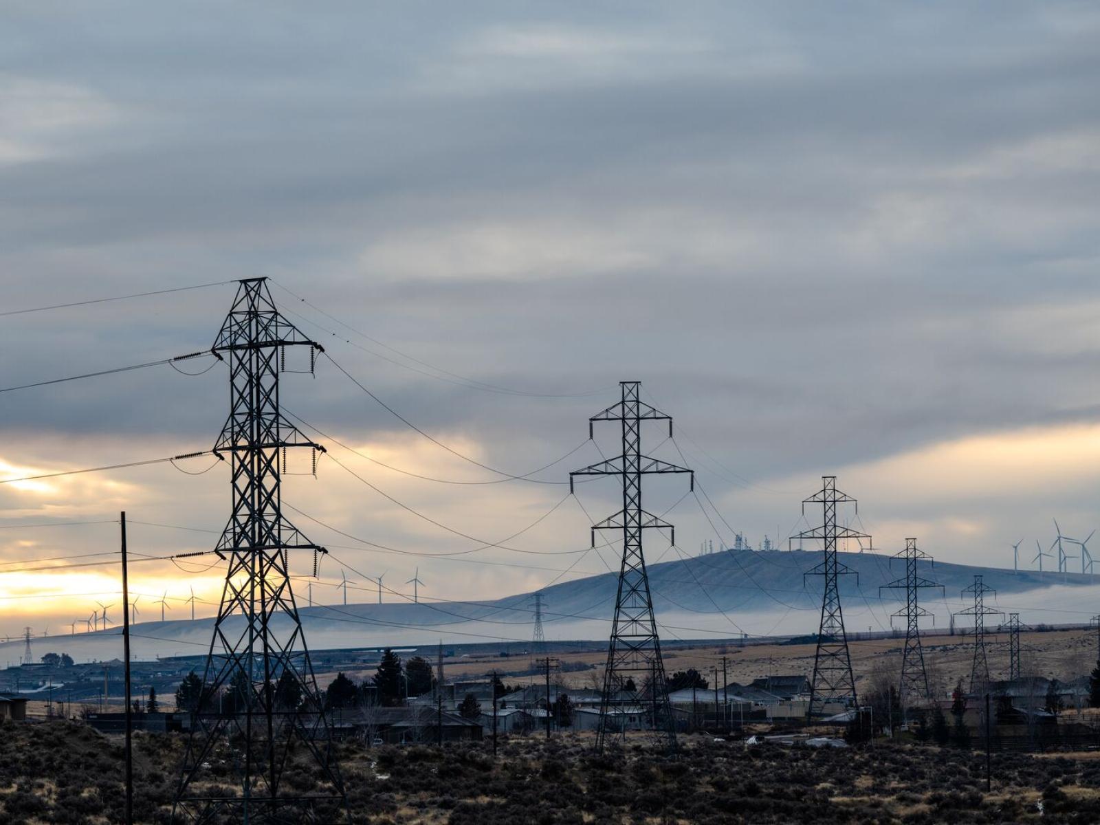 Transmission power line towers against a cloudy sky.