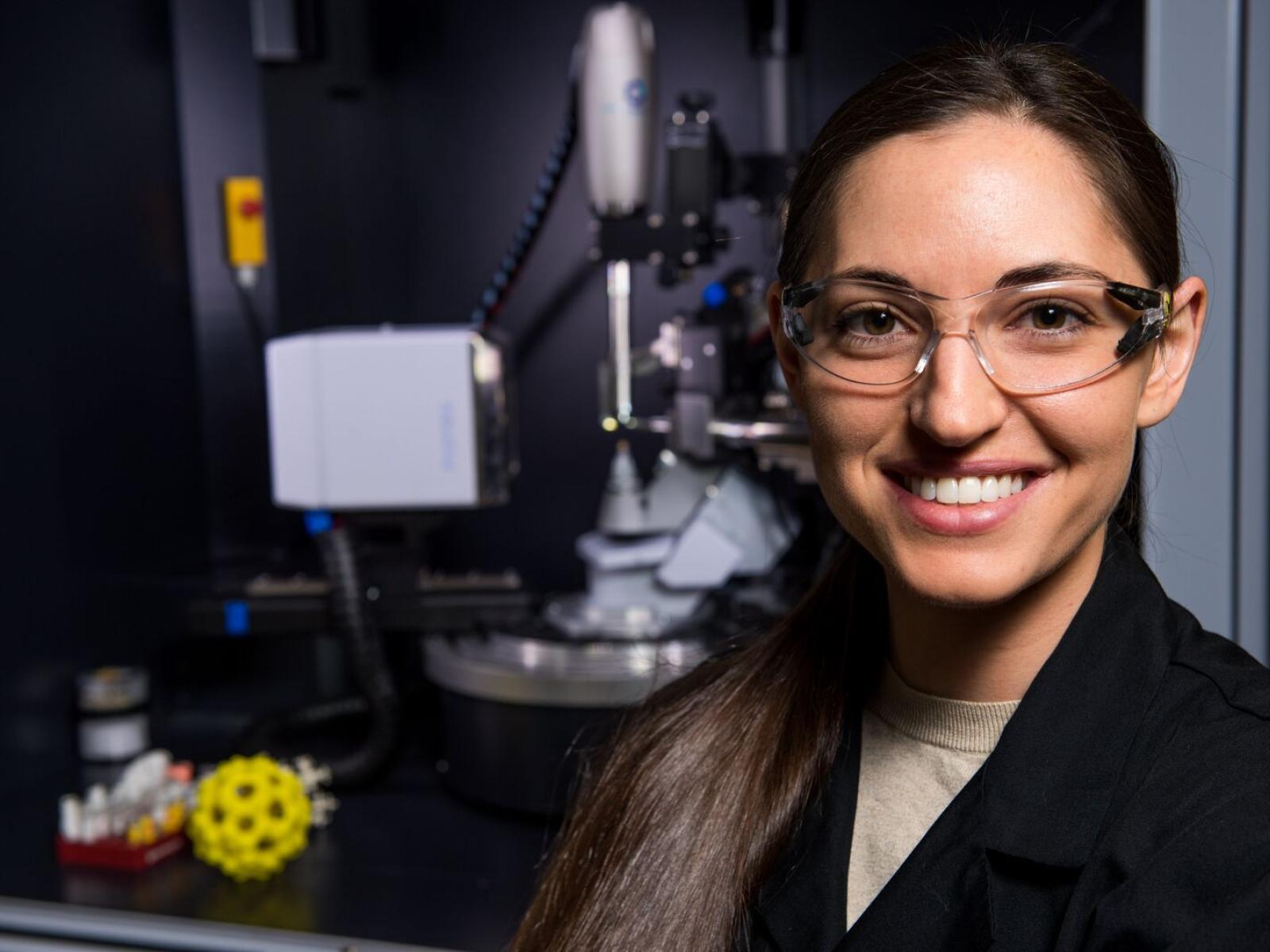 Jordan Corbey, wearing safety eyewear, standing near laboratory equipment