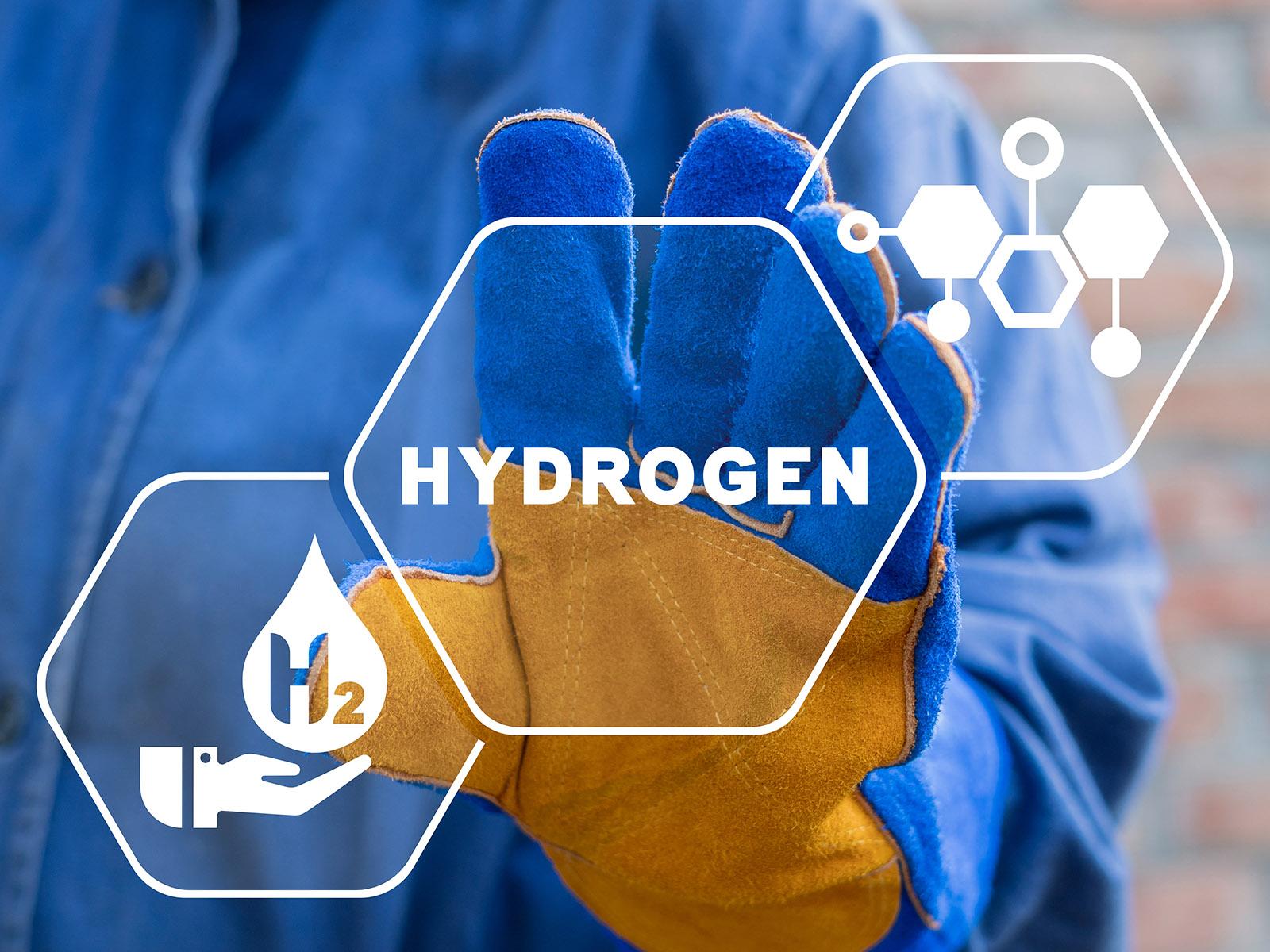 A gloved hand extending towards graphics representing hydrogen fuel.