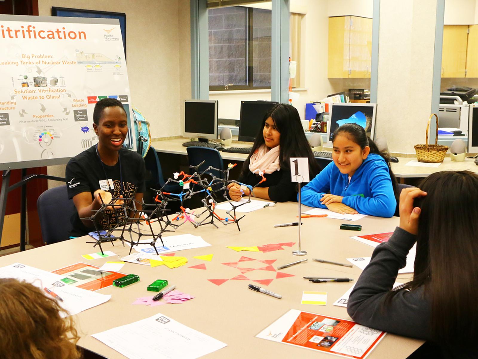STEM Ambassador Charmayne Lonergan at a traditional on-site STEM outreach event in a school classroom surrounded by students.