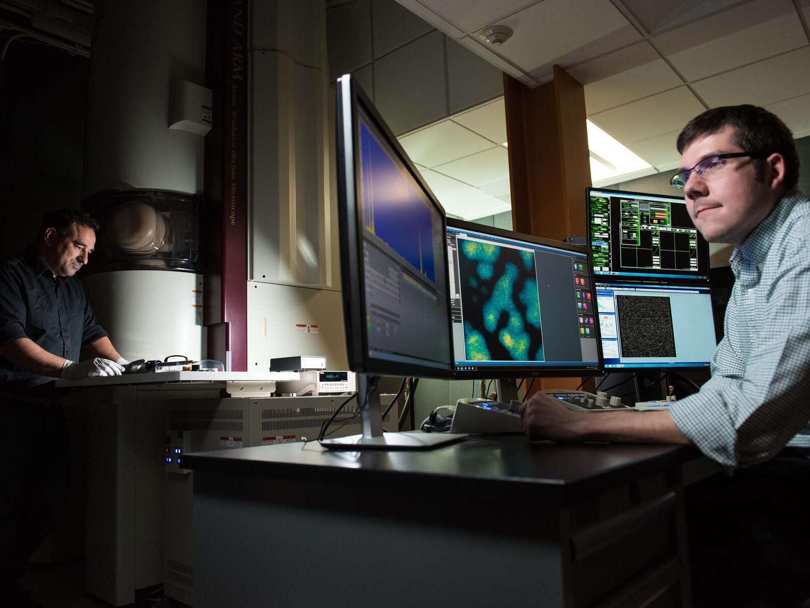 Edgar Buck and Steven Spurgeon, using a large electron microsope to do science research.