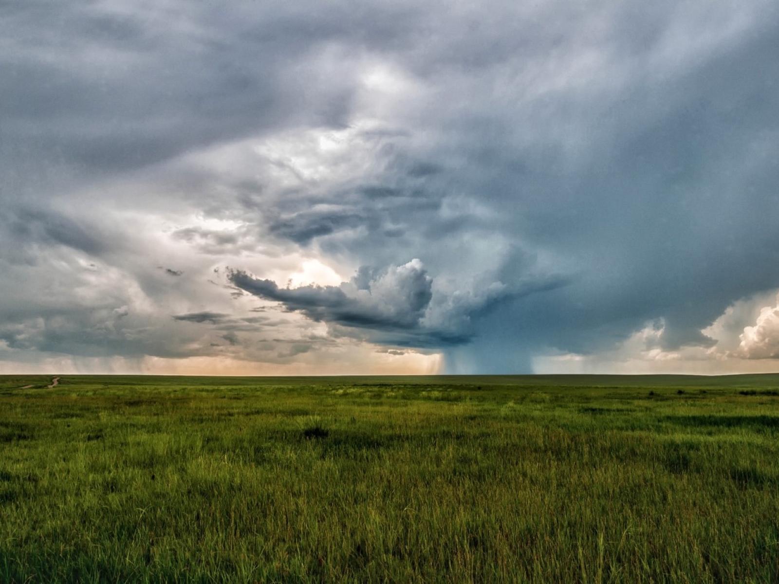 Photograph of a stormy sky above a field of grass.