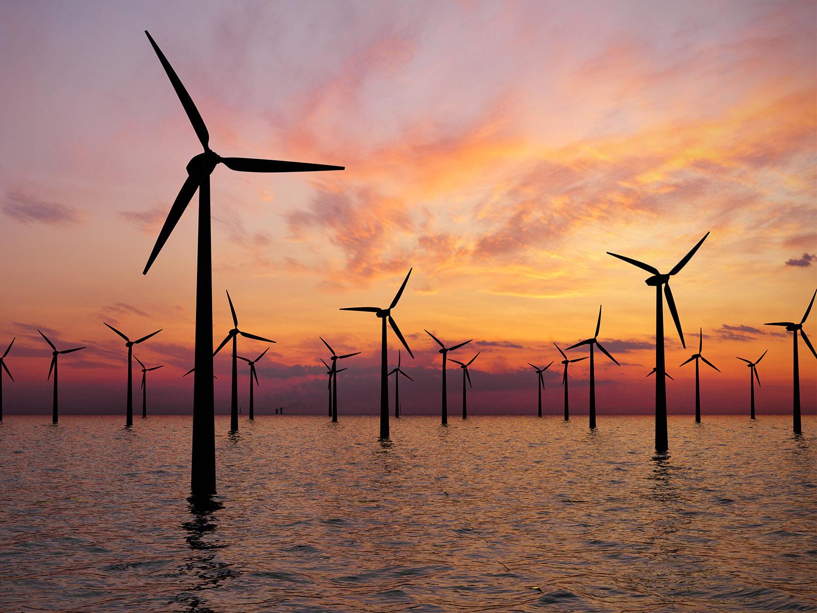 Turbines in water against sunset