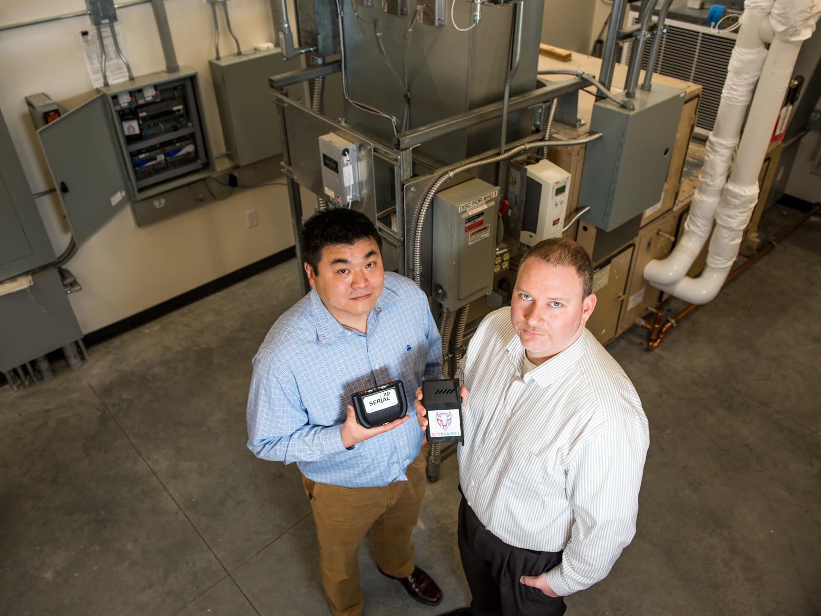 Two researchers hold SerialTap equipment in a facility room