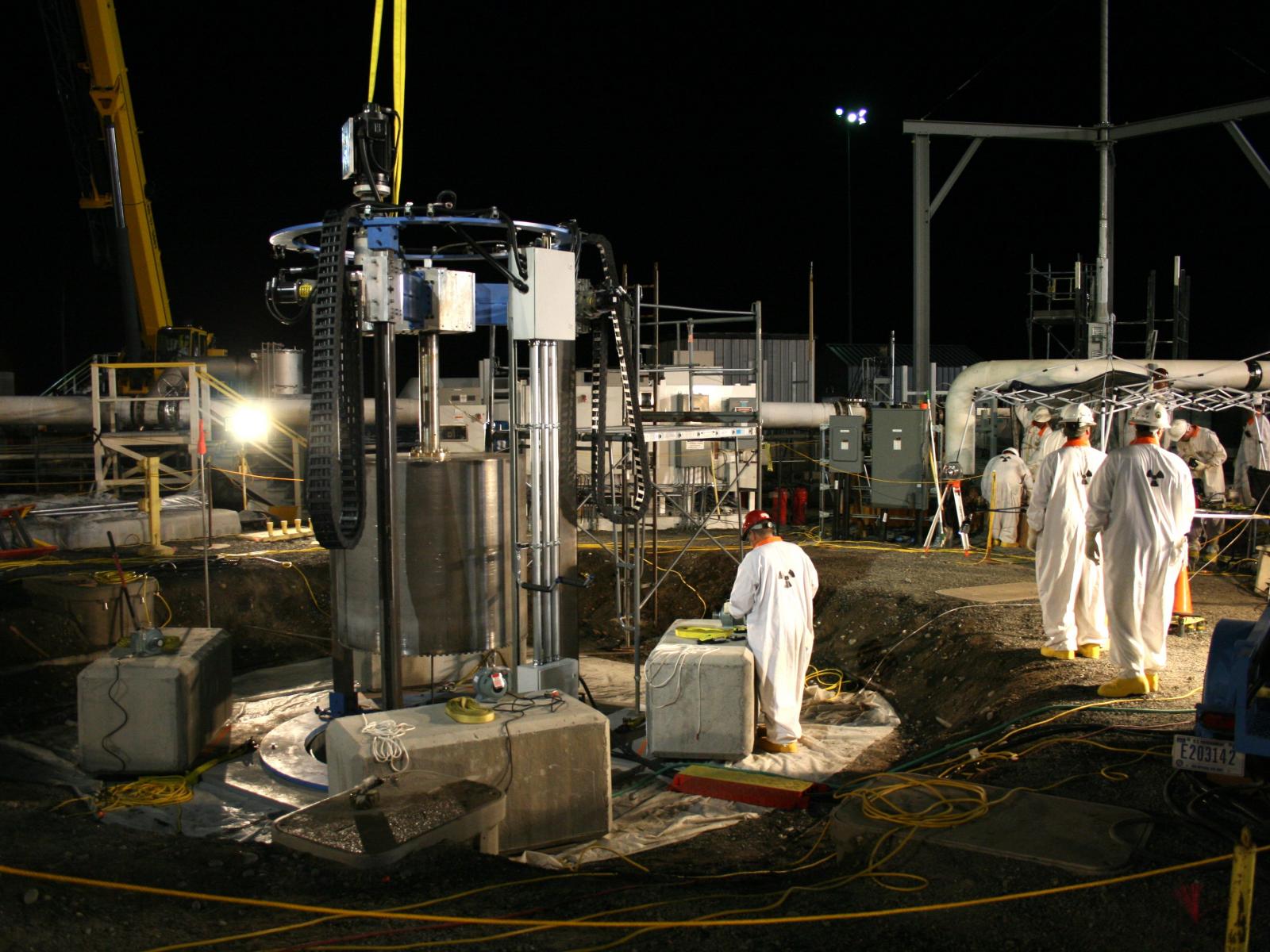 Workers in protective gear use equipment 