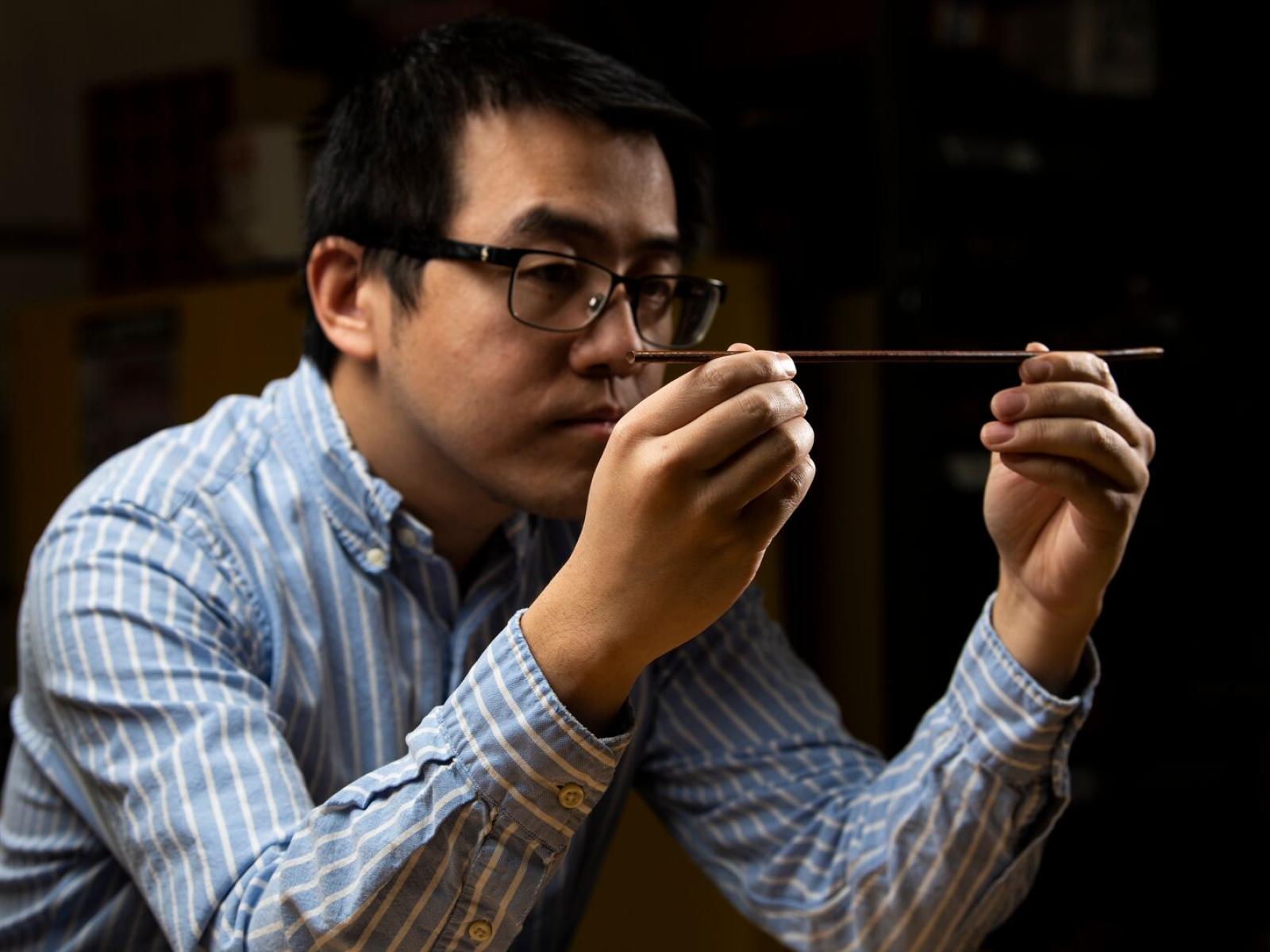 A man holds a piece of metal wire.
