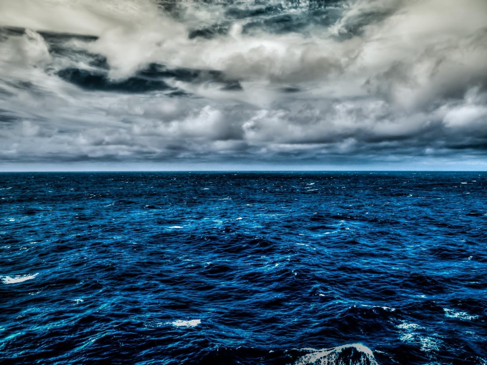 Blue waves below a cloudy sky