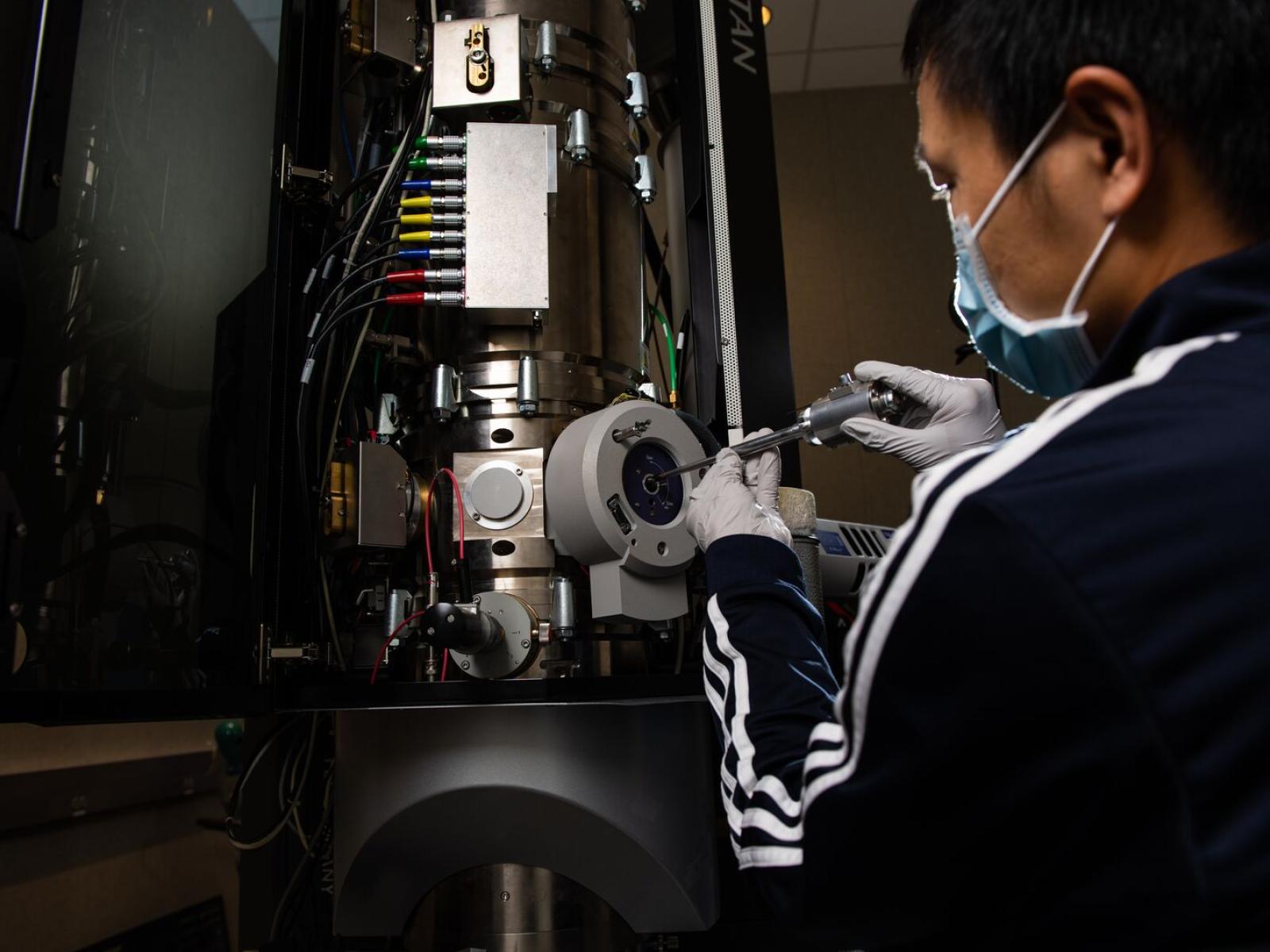 a man works inserts a battery sample into transmission electron microscope