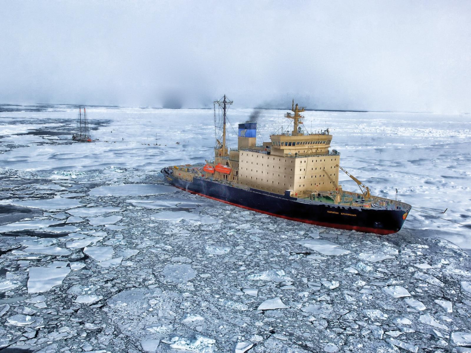 A single ship rests in frigid ocean waters, icy blocks floating all around it, as smoke billows from its exhaust