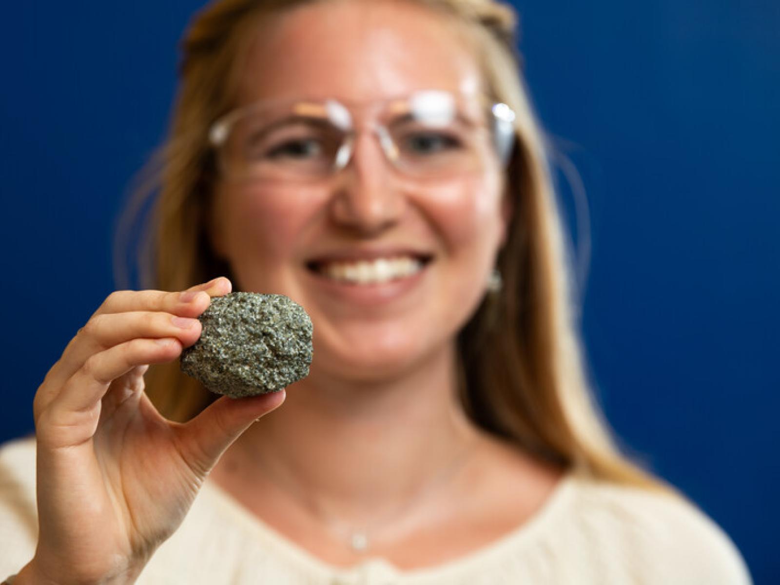 Madeline Bartels smiles and holds a rock sample 