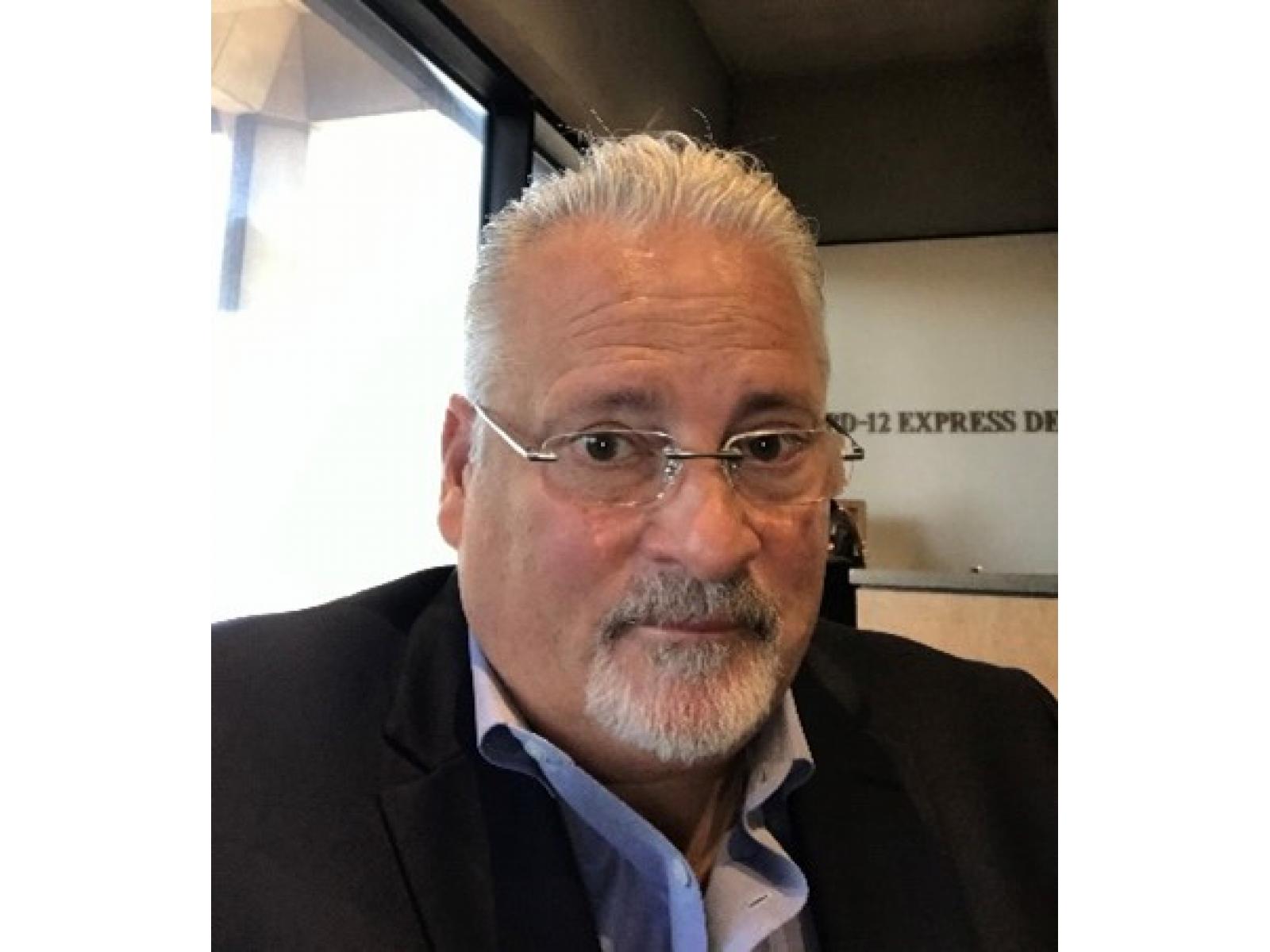 Photo of a man in a suit wearing glasses. 