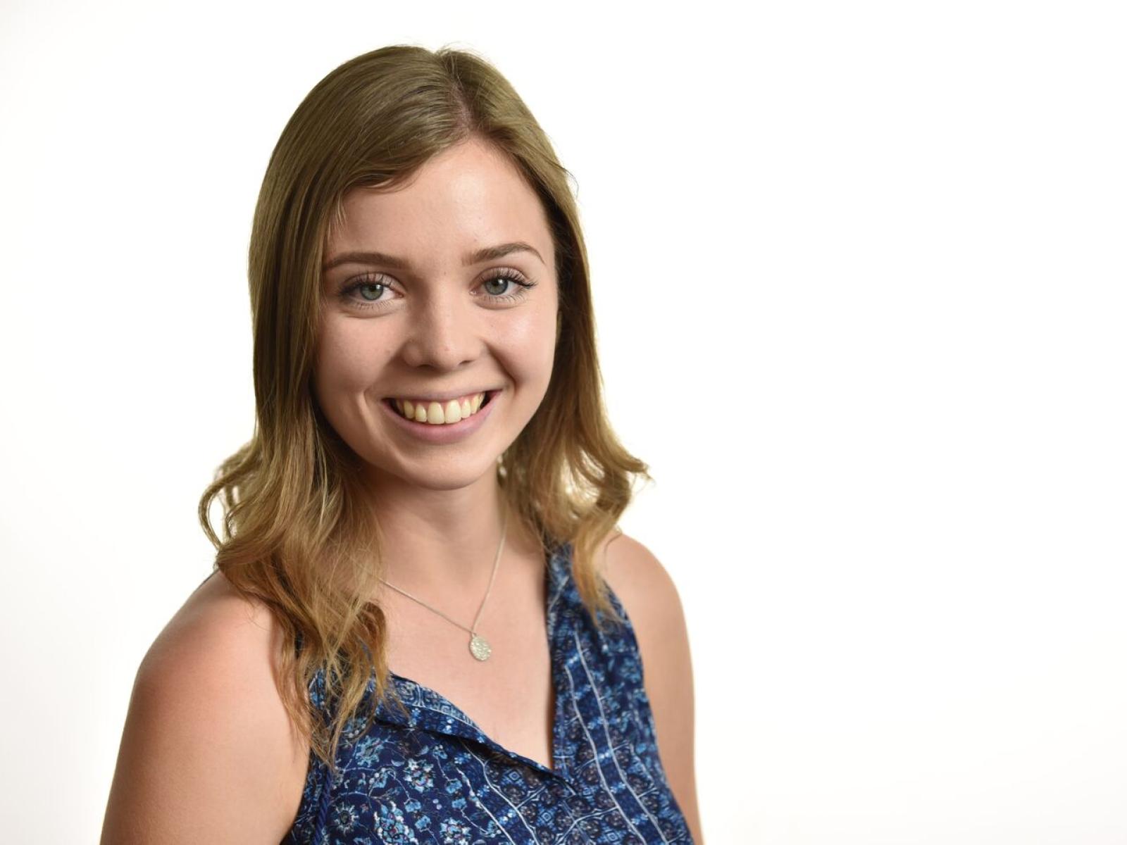 Headshot of Emily Dykes, pictured facing the camera and smiling in a blue tank top