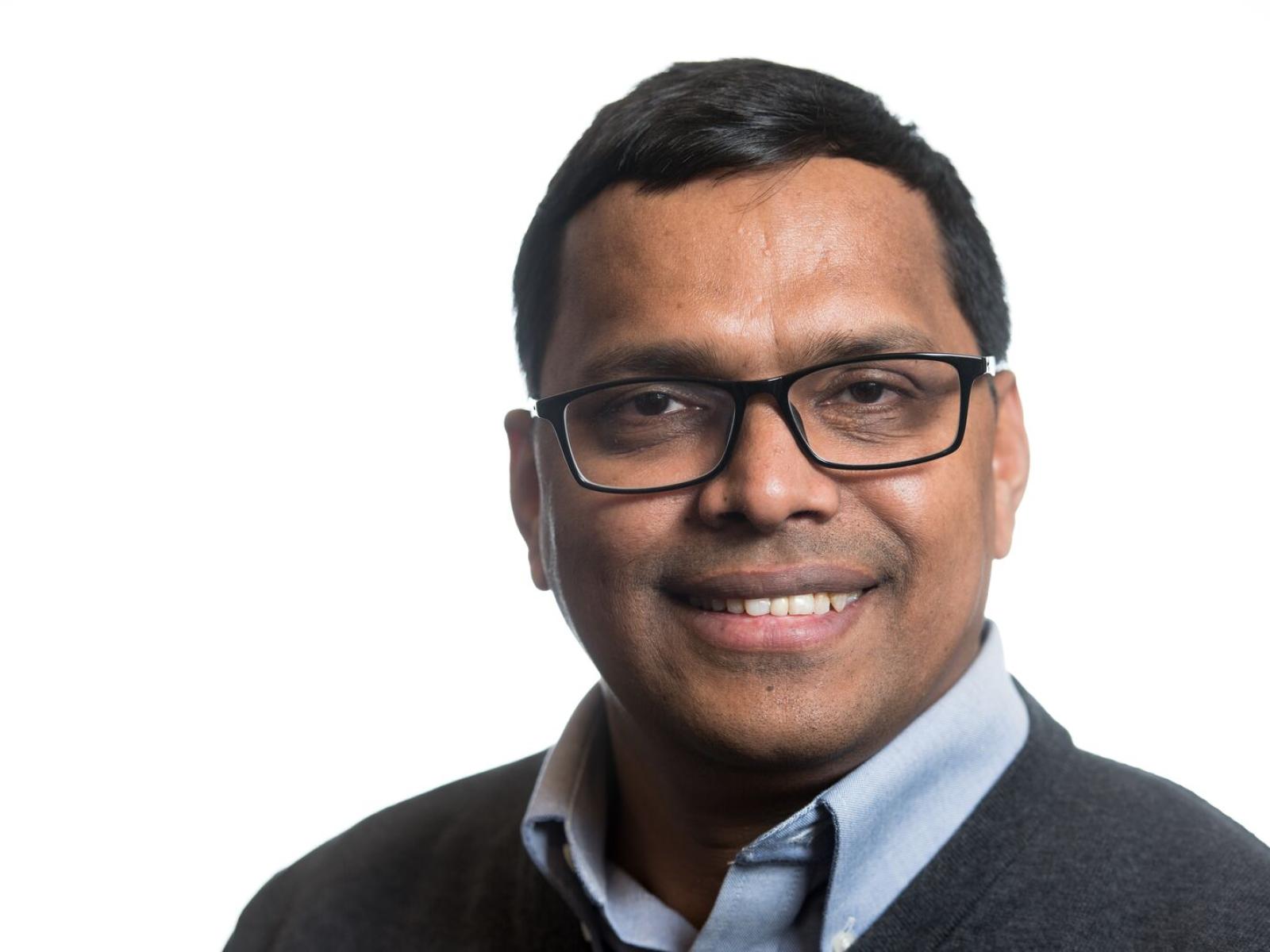 Photograph of a smiling man with glasses in business attire