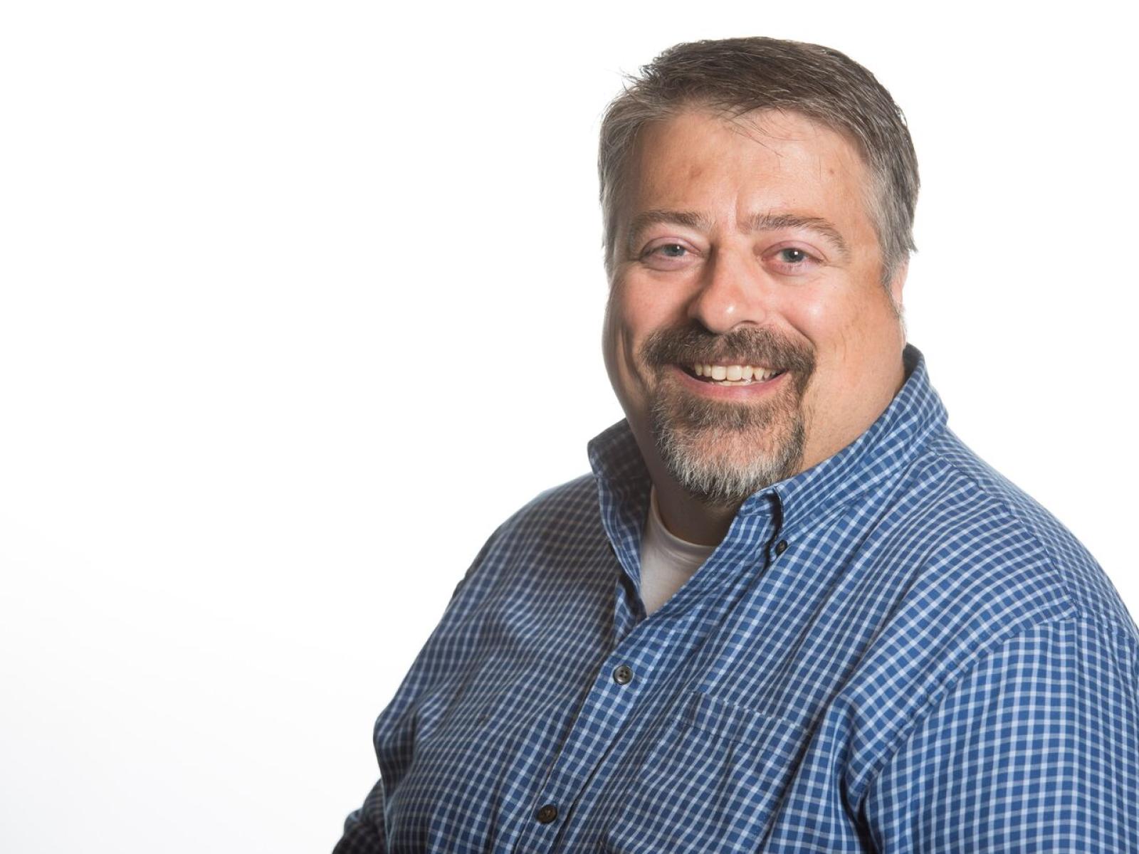 Smiling man with goatee in a blue plaid shirt