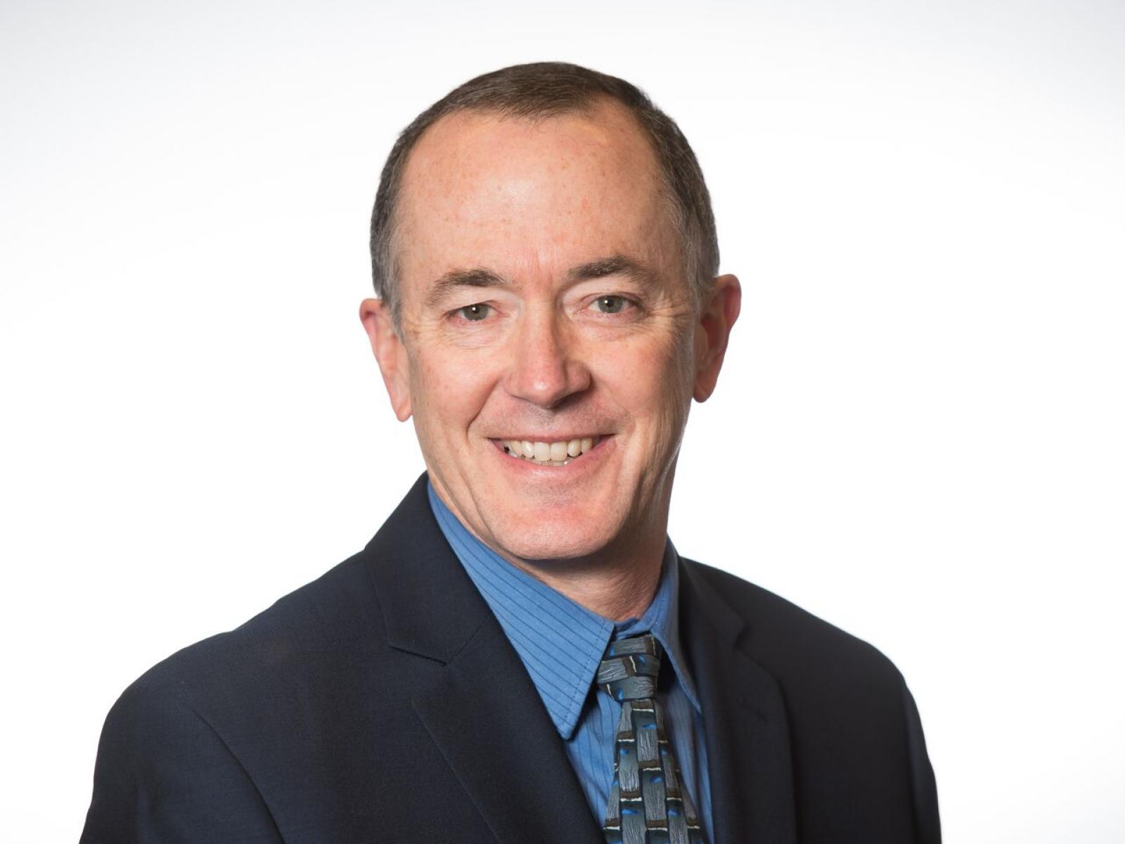 photo of a smiling man in a dark suit and tie