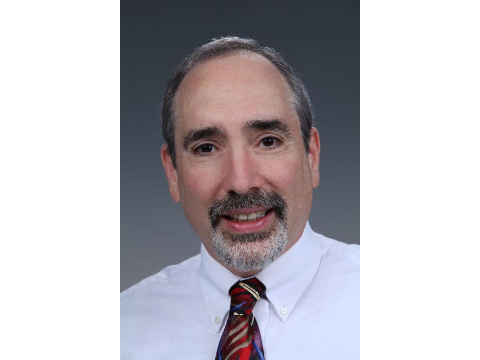 Professional photograph of person wearing white shirt and multi-colored tie.