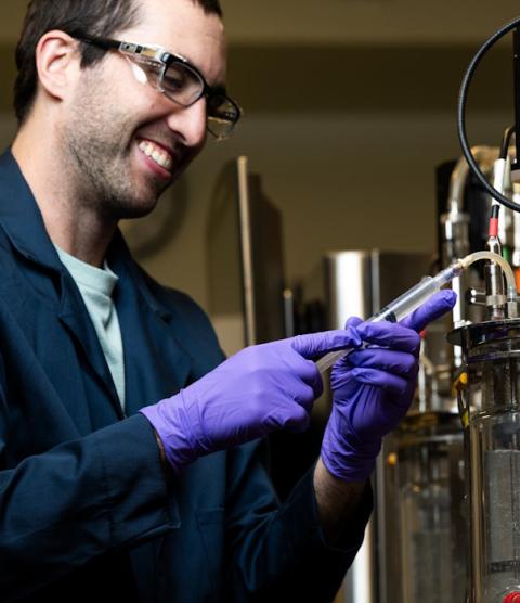 Researcher Jeff Czajka, wearing safety lenses and gloves, operating machinery.