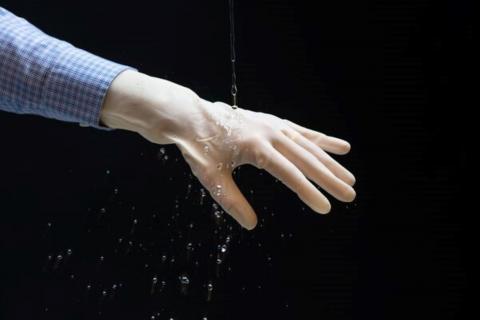Water being poured over a glove coated with ElastiDry