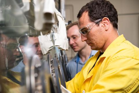 People looking into a scientific hood to work on nuclear materials 