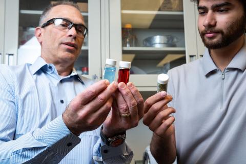 Close up photograph of two men holding vials