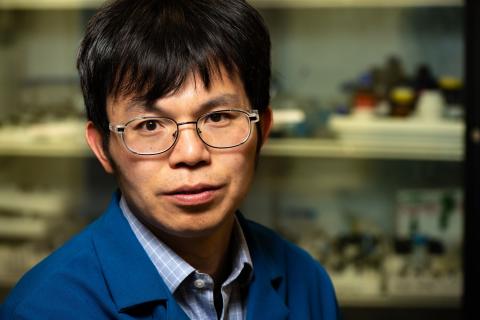 Man with dark hair and blue lab coat