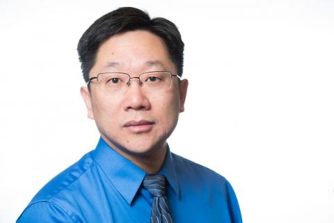 Man with dark hair, glasses and tie.
