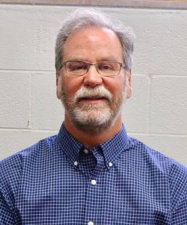 Michael Annable is a middle-aged white man with a short, graying beard, mustache, and glasses, wearing a blue button-down shirt. He is a University of Florida professor of environmental engineering sciences.
