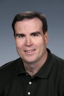 man smiling at camera wearing a dark shirt