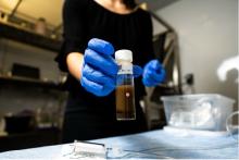 a researcher holds a vial of river sediment and water taken to sample respiration