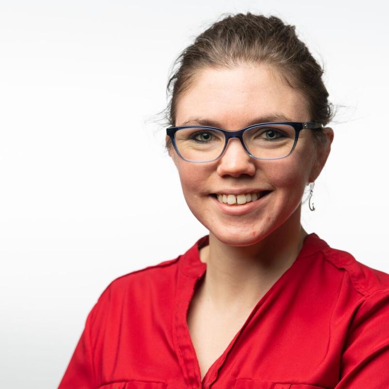Photo of a woman in a red shirt with glasses. 