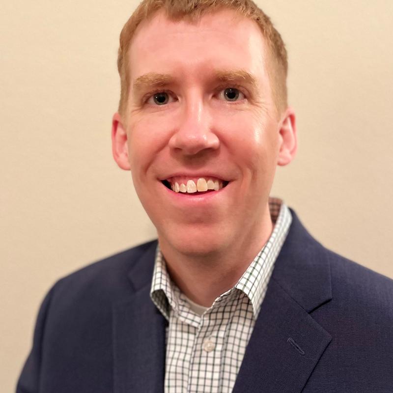 Photograph of a smiling man wearing business attire