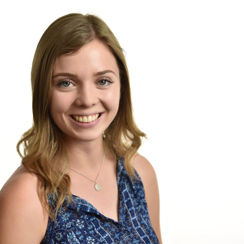 Headshot of Emily Dykes, pictured facing the camera and smiling in a blue tank top