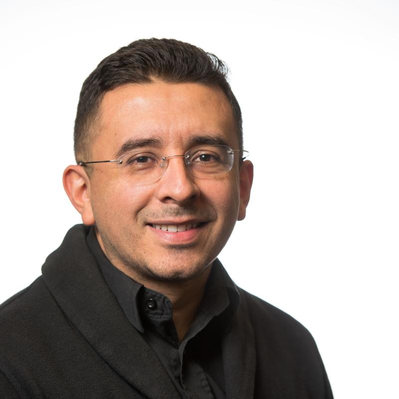 Photo of a man in a black jacket with glasses. 