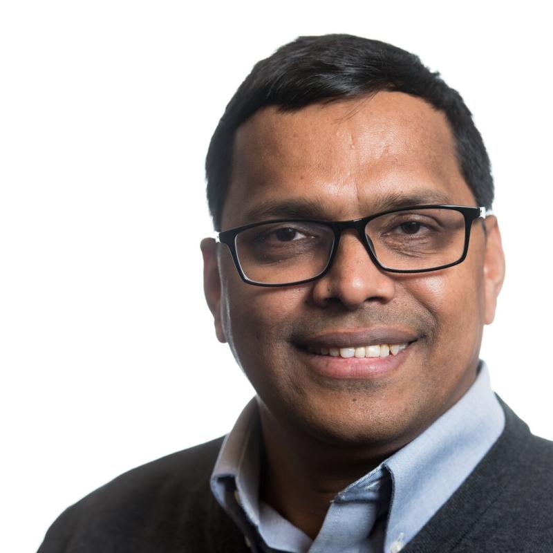 Photograph of a smiling man with glasses in business attire