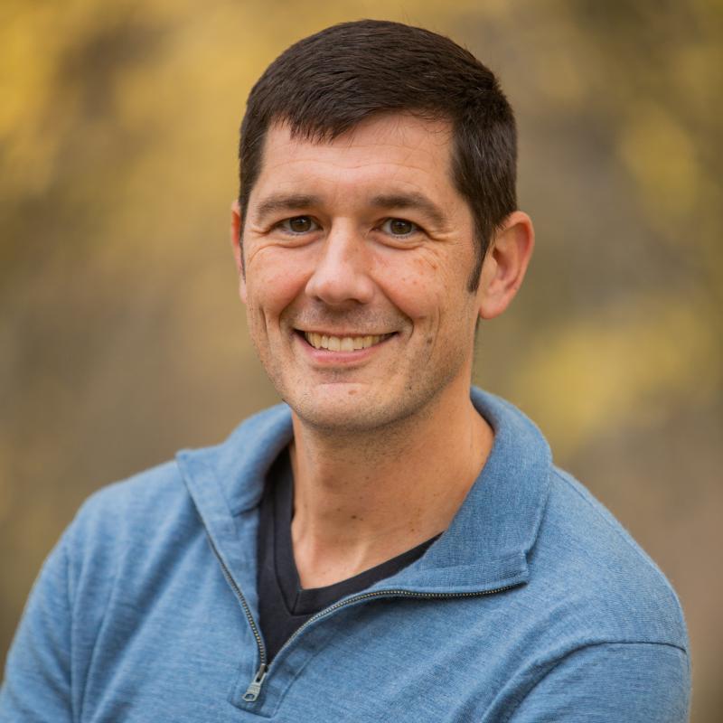 photo of a man with brown hair in a blue sweater. 