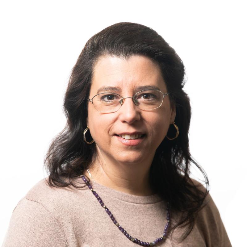 Brown-haired woman with glasses and a dark colored necklace