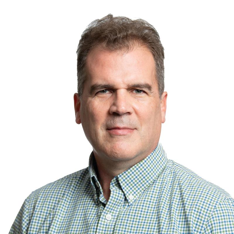 Photograph of a slightly smiling man wearing a patterned dress shirt