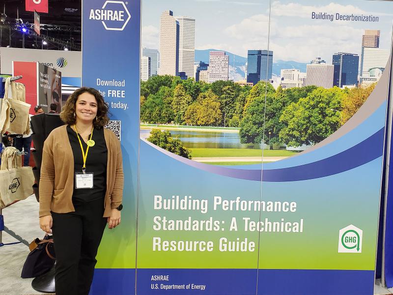 Andrea Mengual stands next to a poster featuring the BPS guide's cover