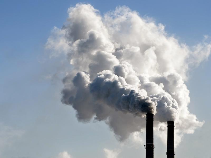 Stacks emitting air pollution against blue sky.