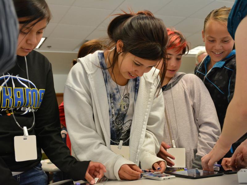 children looking phones and tablets connected to smartphone microscopes