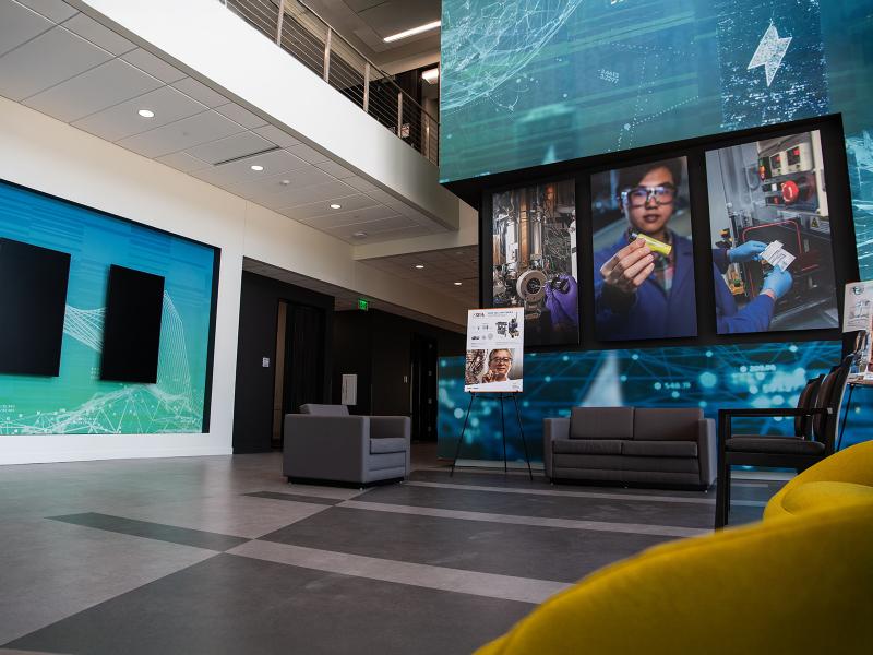 a building lobby with a dark tiled floor, large photos hung on the wall, and blue decorative wall displays
