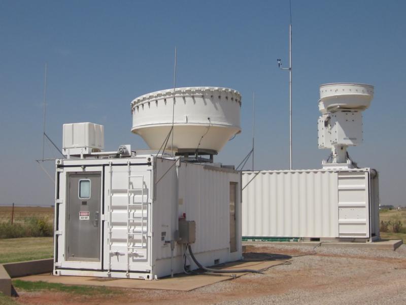 Photograph of white metal buildings with radar equipment on top