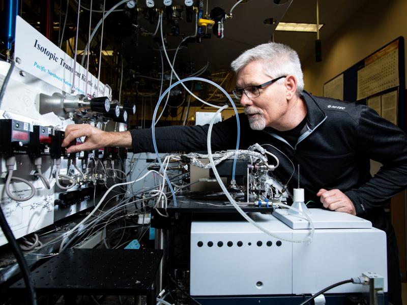 Male scientist reaching to adjust equipment