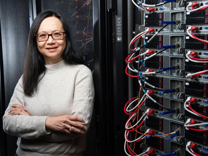Margaret Cheung stands next to a wall of scientific instruments.