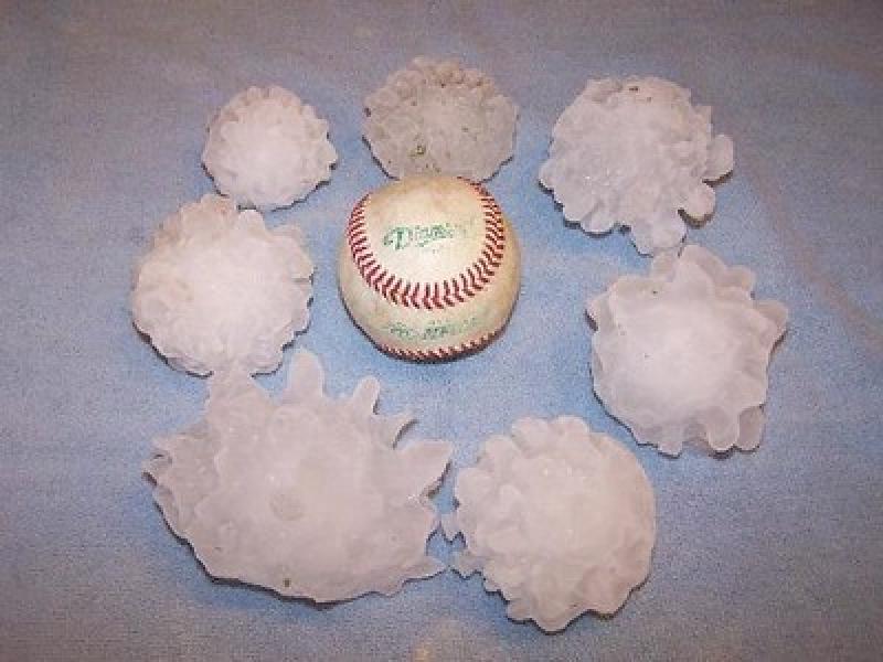 Seven large hailstones surrounding a similarly-sized baseball