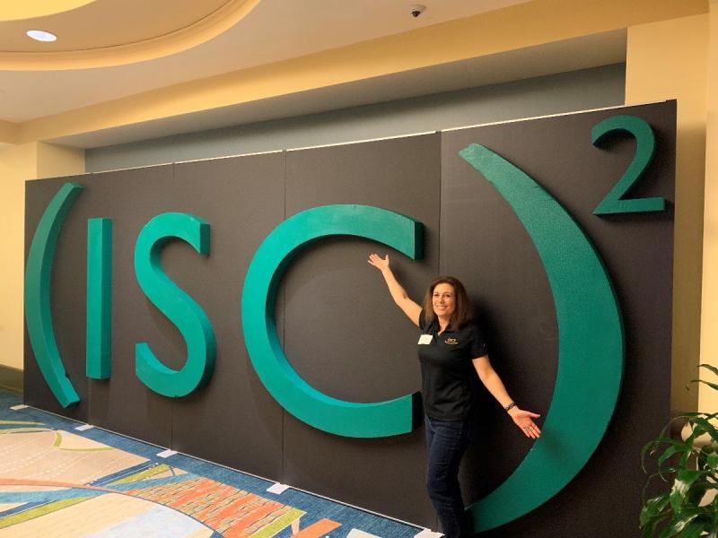 a woman standing in front of a green sign that says ISC2