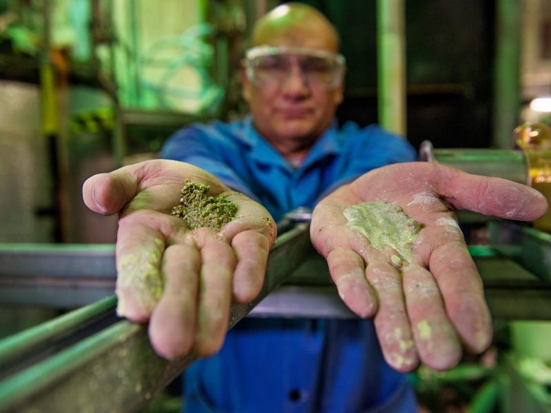 Michael Minette extends his hands, each with a different size of muddy sludge that was separated through the puck-like device.